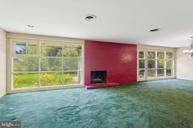unfurnished living room featuring carpet floors, a chandelier, a wealth of natural light, and a fireplace
