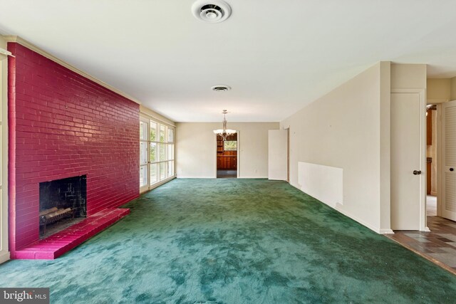 unfurnished living room with a notable chandelier, a fireplace, carpet, baseboards, and visible vents