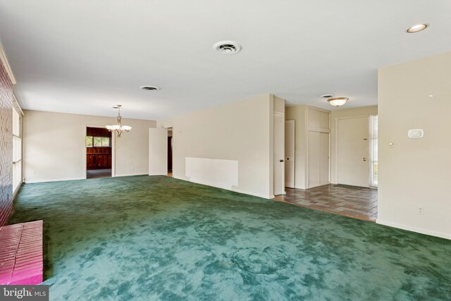 unfurnished living room featuring visible vents, baseboards, a chandelier, and carpet