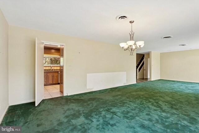 carpeted empty room featuring visible vents, baseboards, an inviting chandelier, and stairway