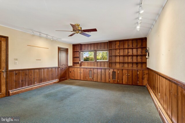 carpeted spare room featuring track lighting, wooden walls, and baseboard heating