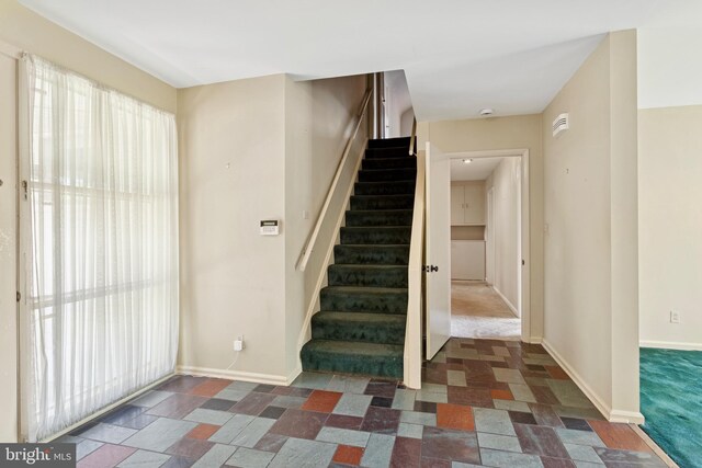 staircase featuring baseboards and stone finish flooring