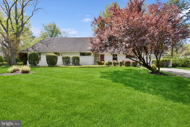 ranch-style home with a front lawn and roof with shingles