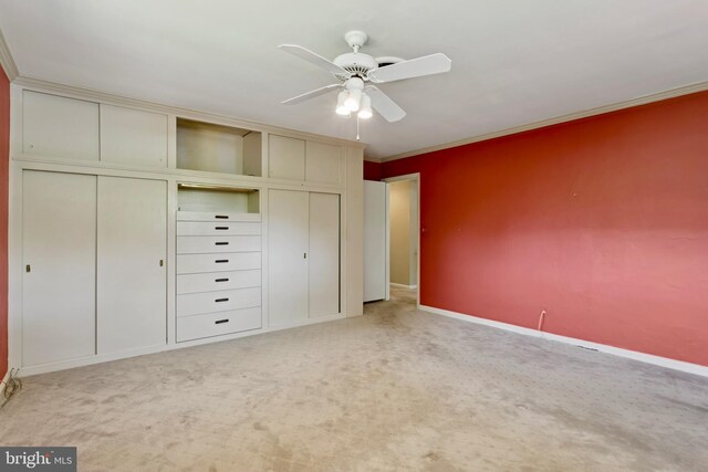 unfurnished bedroom featuring a ceiling fan, light colored carpet, crown molding, baseboards, and a closet
