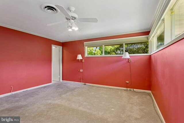 empty room featuring ceiling fan, visible vents, crown molding, baseboards, and carpet flooring