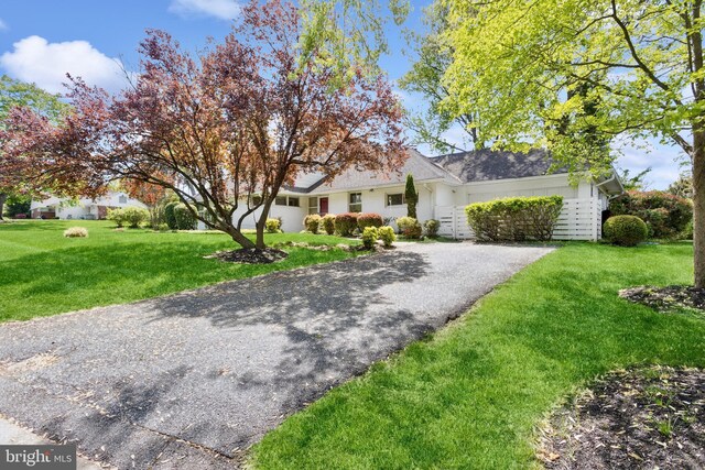 view of front of property featuring an attached garage, a front lawn, and driveway