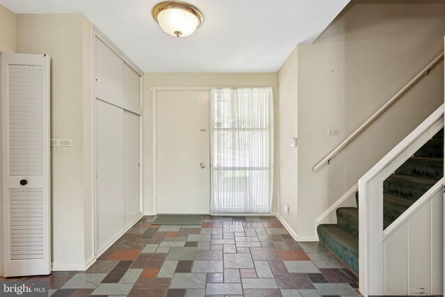 entryway featuring stairs, baseboards, and stone tile flooring