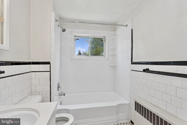 bathroom featuring  shower combination, radiator, toilet, and tile walls