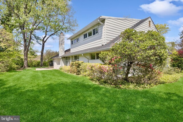view of side of home with a yard and a chimney