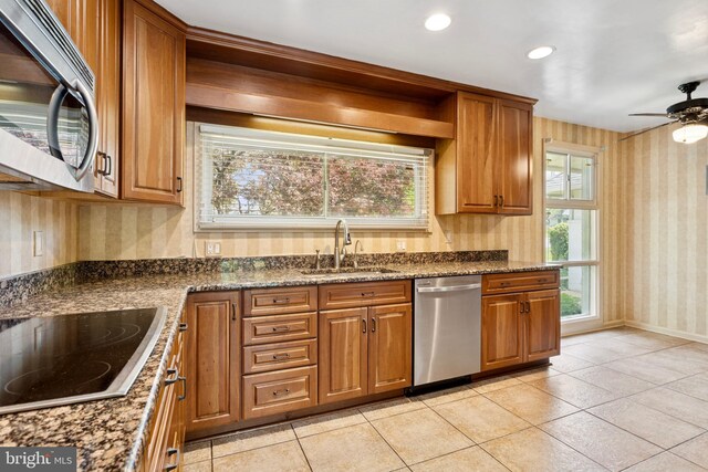 kitchen featuring brown cabinets, stainless steel appliances, wallpapered walls, and a sink