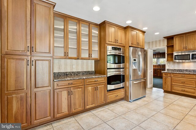 kitchen featuring open shelves, decorative backsplash, appliances with stainless steel finishes, and brown cabinets