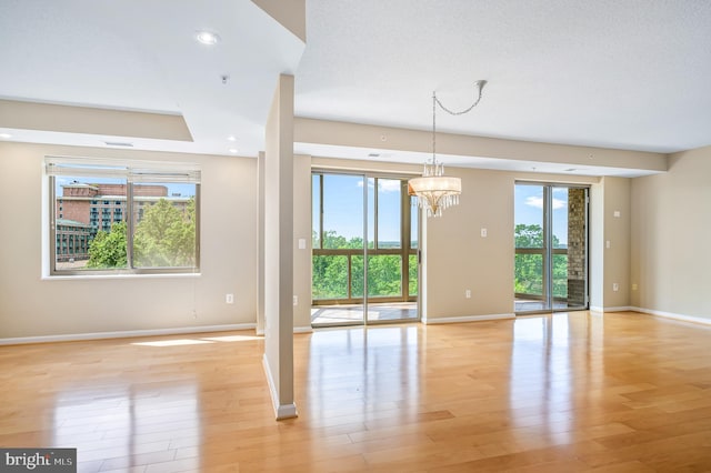 unfurnished dining area with light wood-style floors, baseboards, a chandelier, and recessed lighting