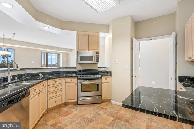 kitchen featuring appliances with stainless steel finishes, light brown cabinetry, a sink, light stone finish floors, and recessed lighting