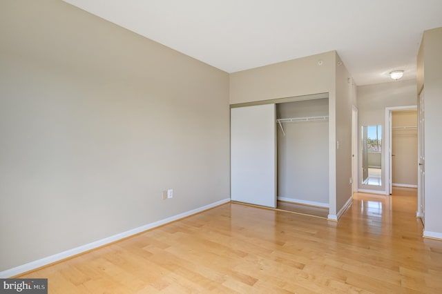 unfurnished bedroom with light wood-style floors, baseboards, and a closet