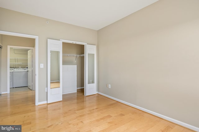 unfurnished bedroom with independent washer and dryer, baseboards, light wood finished floors, and a closet