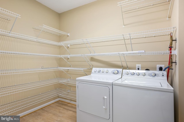 clothes washing area with washing machine and clothes dryer and light wood finished floors