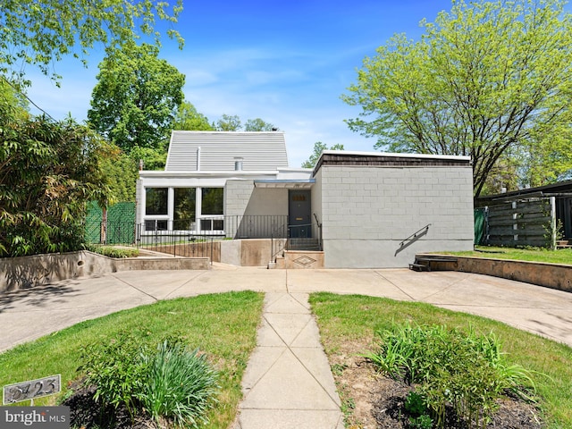 rear view of house with concrete block siding and fence