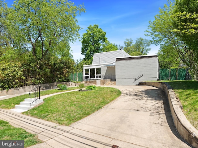 rear view of house featuring a lawn and fence