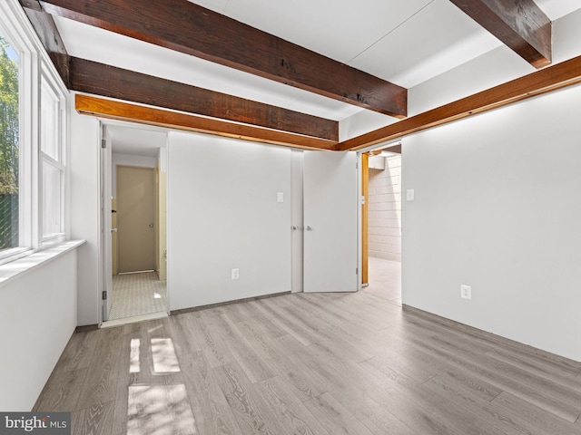 empty room with beam ceiling and wood finished floors