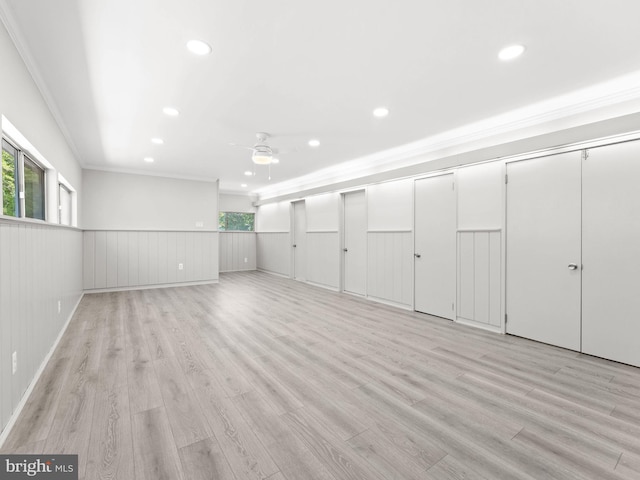 below grade area featuring recessed lighting, ornamental molding, light wood-style floors, and a wainscoted wall