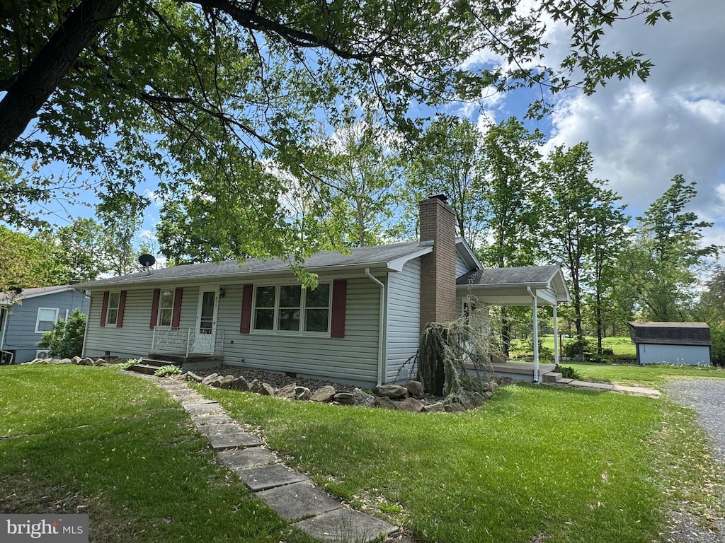 single story home featuring a storage shed, a chimney, an outdoor structure, and a front yard
