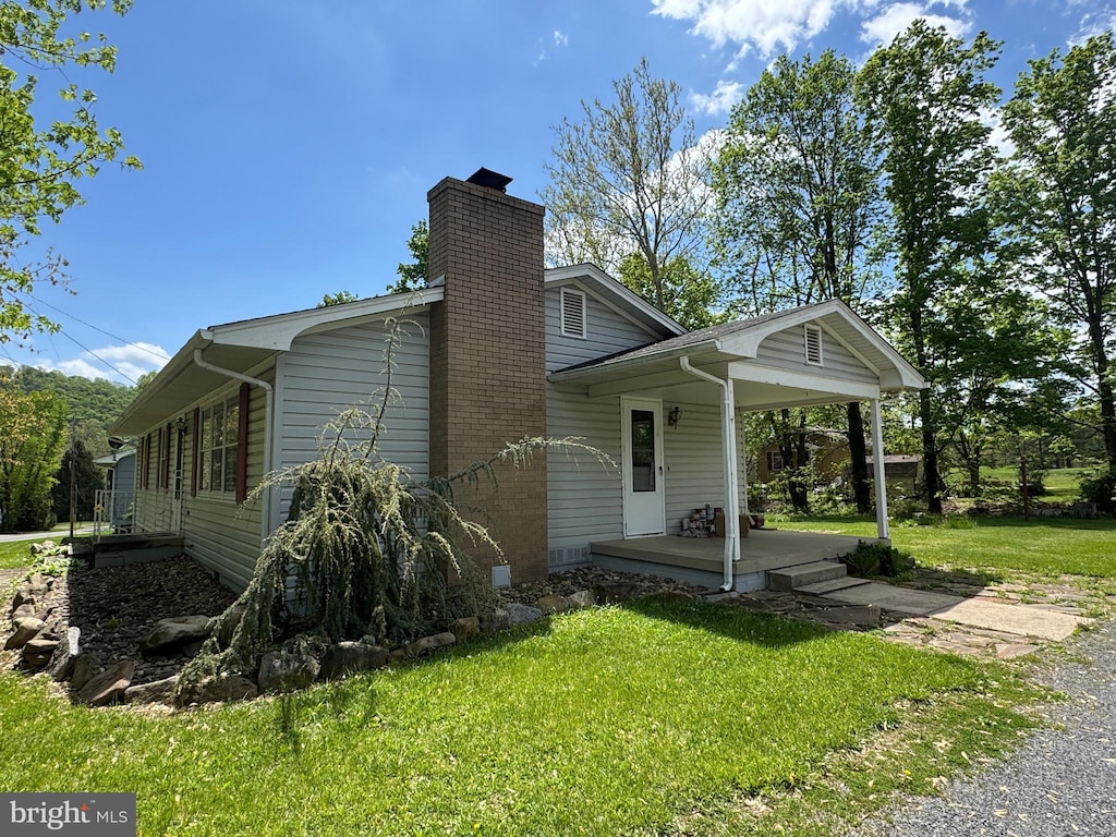 exterior space with a yard, a chimney, and covered porch