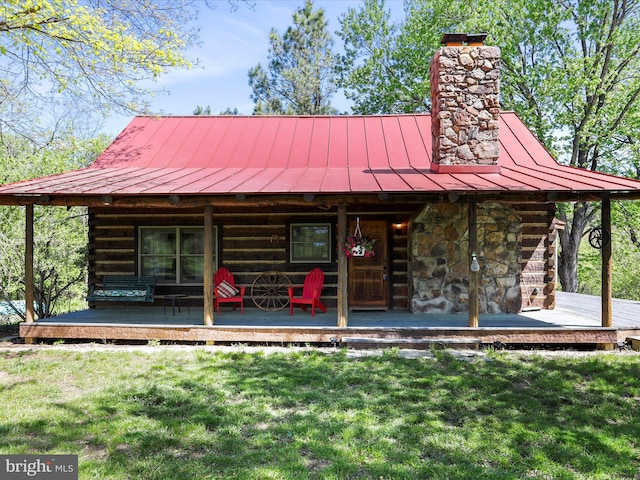 log home with log exterior, a front yard, a chimney, a standing seam roof, and metal roof