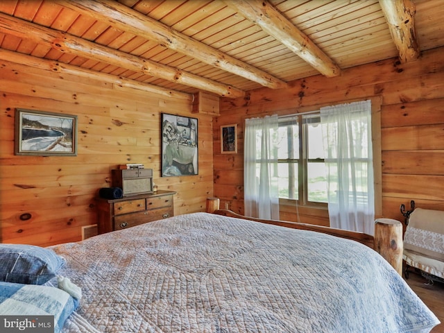 bedroom with wood walls, beam ceiling, and wood finished floors