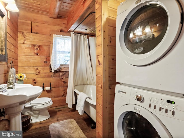 bathroom with toilet, wood walls, hardwood / wood-style floors, wooden ceiling, and stacked washer / dryer