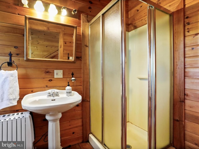 bathroom with radiator heating unit, a stall shower, and wood walls