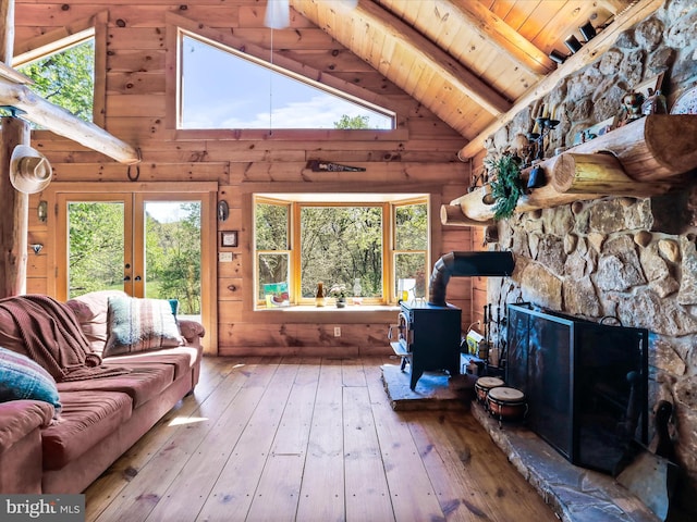 living area with a wood stove, beam ceiling, wooden ceiling, hardwood / wood-style floors, and a wealth of natural light