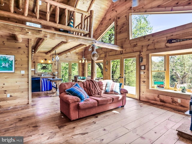 living area featuring wood ceiling, french doors, wood-type flooring, lofted ceiling with beams, and wooden walls