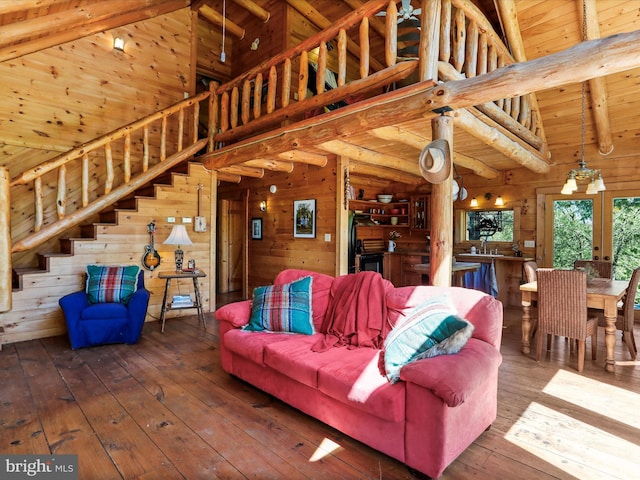 living area with high vaulted ceiling, beamed ceiling, wooden walls, stairs, and hardwood / wood-style floors