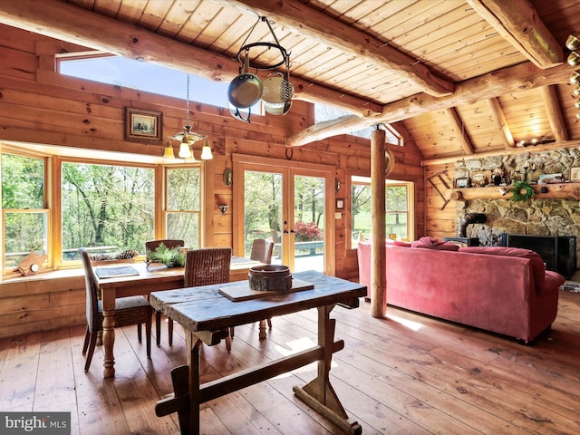 dining space with wooden walls, wooden ceiling, french doors, and light wood-style floors