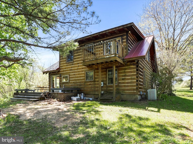 rear view of property featuring a yard, a deck, metal roof, and a balcony