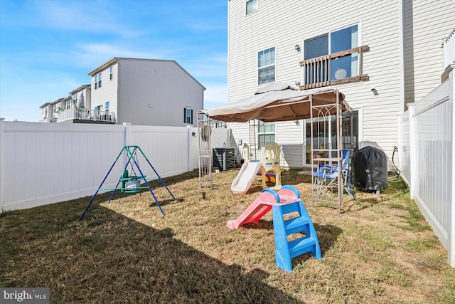 view of jungle gym featuring a gazebo, central AC unit, a yard, and a fenced backyard