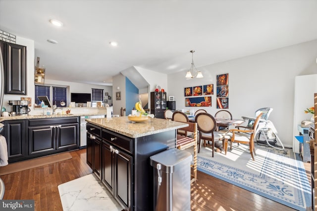 kitchen with dark wood finished floors, an inviting chandelier, a sink, and light stone counters