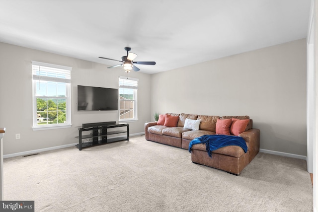 carpeted living area featuring plenty of natural light, ceiling fan, and baseboards