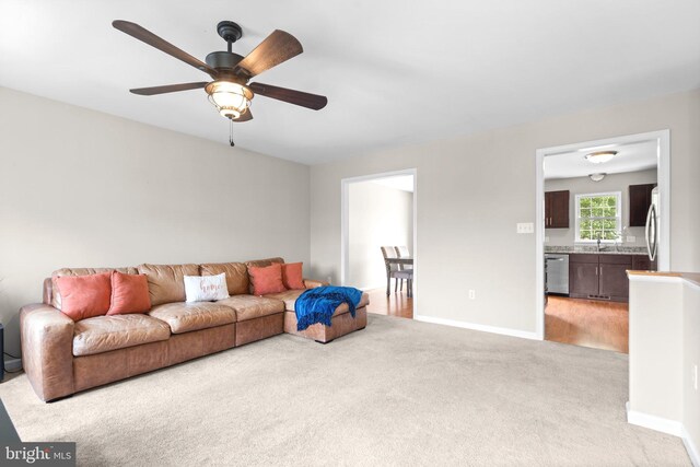 living room featuring light carpet, ceiling fan, and baseboards