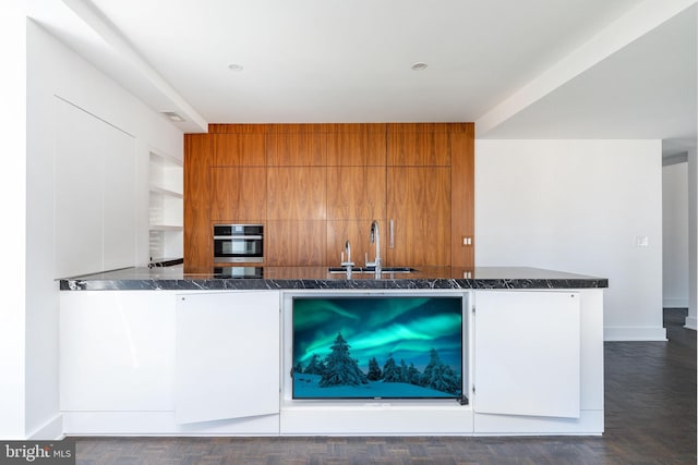 1830 Rittenhouse Sq Unit 17B, Philadelphia, PA 19103 - kitchen featuring brown cabinetry, oven, modern cabinets, dark stone counters, and a sink