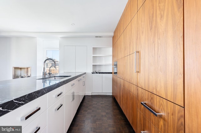 1830 Rittenhouse Sq Unit 17B, Philadelphia, PA 19103 - kitchen with visible vents, modern cabinets, dark stone counters, white cabinetry, and a sink