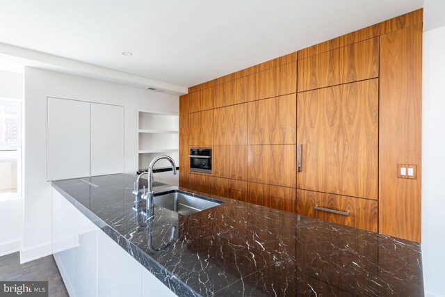 1830 Rittenhouse Sq Unit 17B, Philadelphia, PA 19103 - kitchen featuring baseboards, a sink, dark stone countertops, and brown cabinets