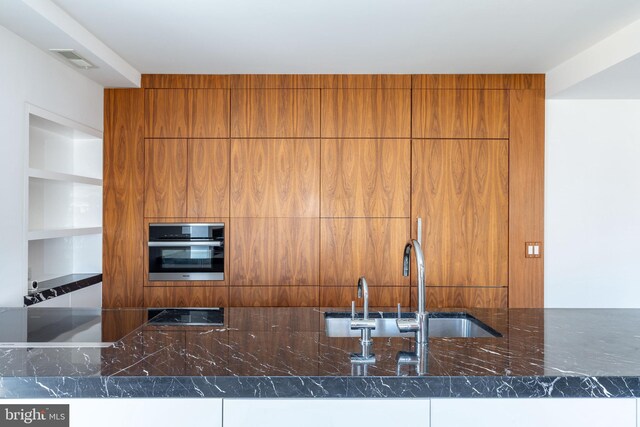 1830 Rittenhouse Sq Unit 17B, Philadelphia, PA 19103 - kitchen featuring brown cabinets, dark stone counters, wall oven, visible vents, and modern cabinets