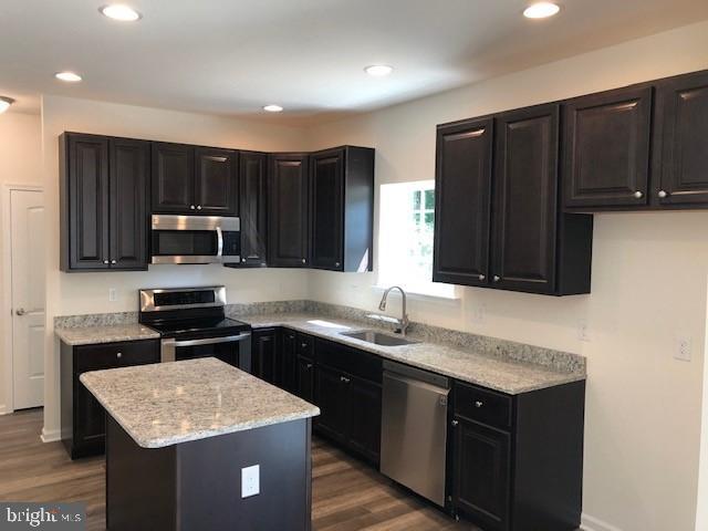 308 Nowland Ln, Delaware City, DE 19706 - kitchen with appliances with stainless steel finishes, dark cabinets, a kitchen island, and a sink