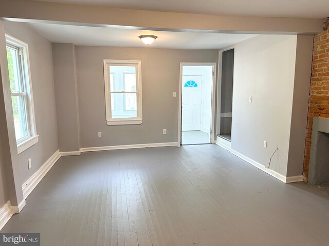 empty room with baseboards, plenty of natural light, and dark wood finished floors