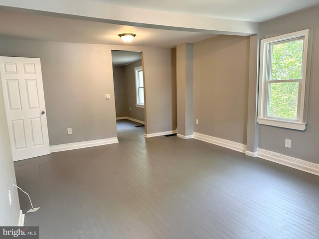 unfurnished room featuring baseboards and dark wood finished floors