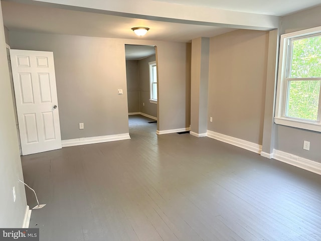 spare room featuring baseboards and dark wood-type flooring