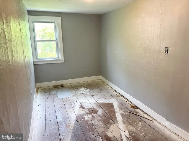 spare room featuring wood-type flooring and baseboards
