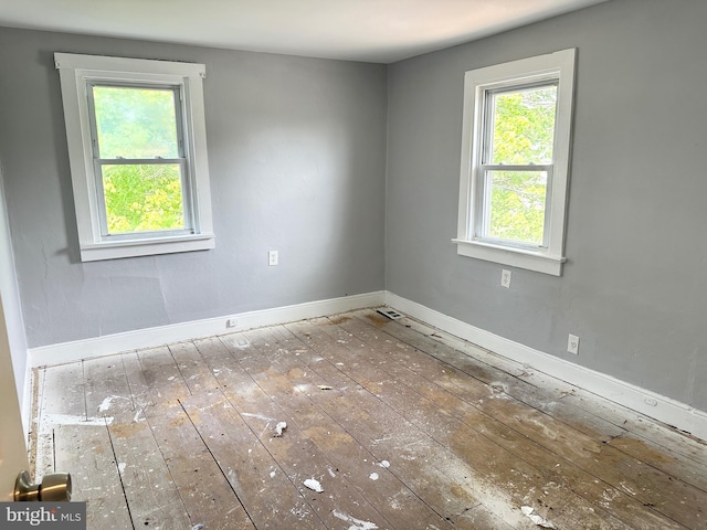 unfurnished room with baseboards and hardwood / wood-style flooring