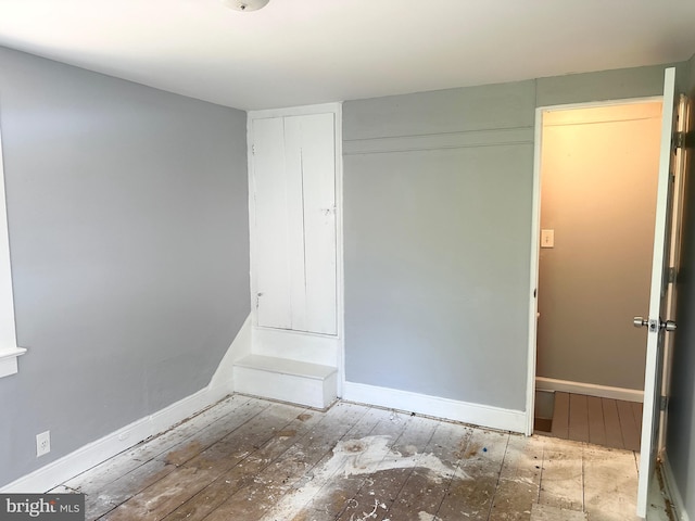 unfurnished bedroom with baseboards, a closet, and hardwood / wood-style floors